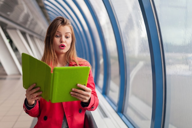 Young pretty woman with surprised face experssion holding tablet laptop in urban building