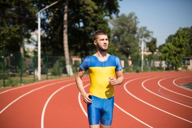 Young professional sportsman running on treadmill of city stadium