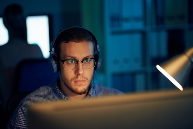 Free photo young programmer in eyewear and headphones working in office