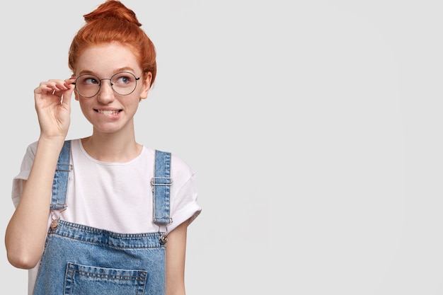 Free photo young red-headed woman in denim overalls