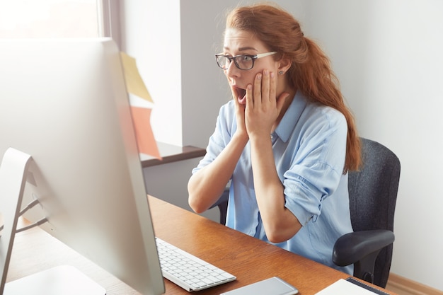 Young redhead female student wearing glasses and blue shirt looking stressed