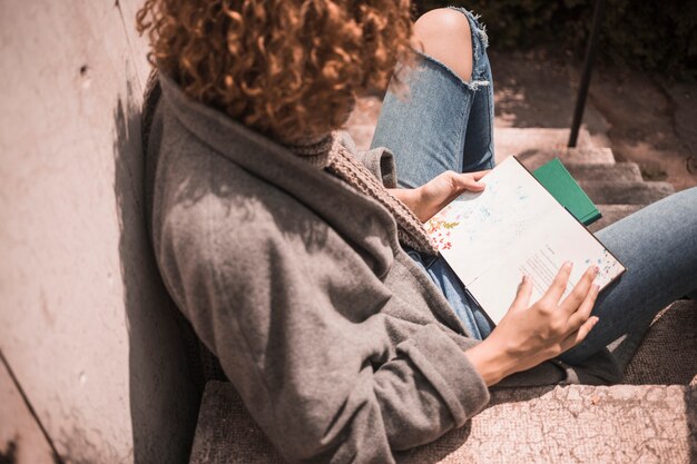 Young redhead female with book on stair