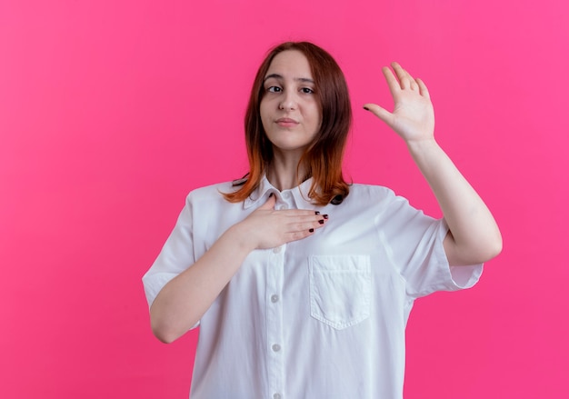 Free photo young redhead girl putting hand on chest and showing stop gesture isolated on pink wall