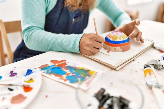 Free Photo young redhead man painting clay pottery at art studio