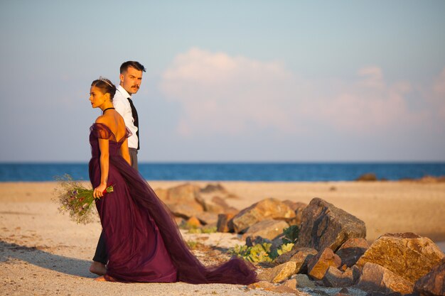 Young romantic couple relaxing on the beach watching the sunset