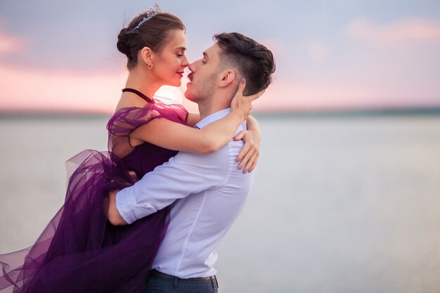 Young romantic couple relaxing on the beach watching the sunset