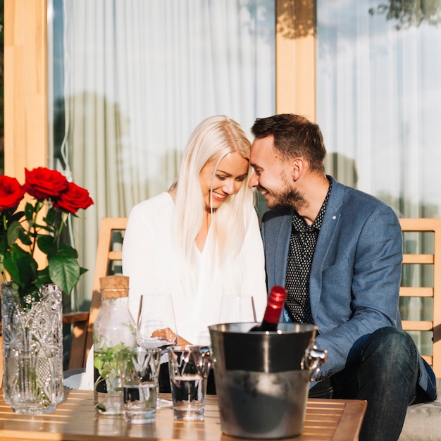 Free Photo young romantic couple sitting behind the table with wine bottle in ice bucket