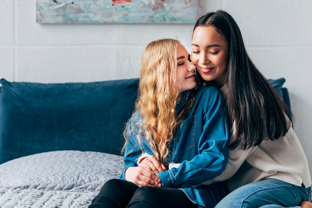 Young romantic lesbian sweethearts sitting on bed