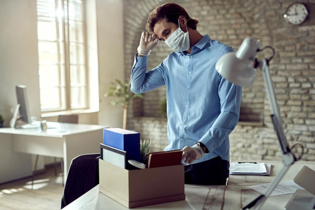 Free photo young sad businessman packing his belongings after being fired during covid19 pandemic