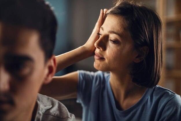 Young sad woman wiping her tears while having problem in a relationship with her boyfriend