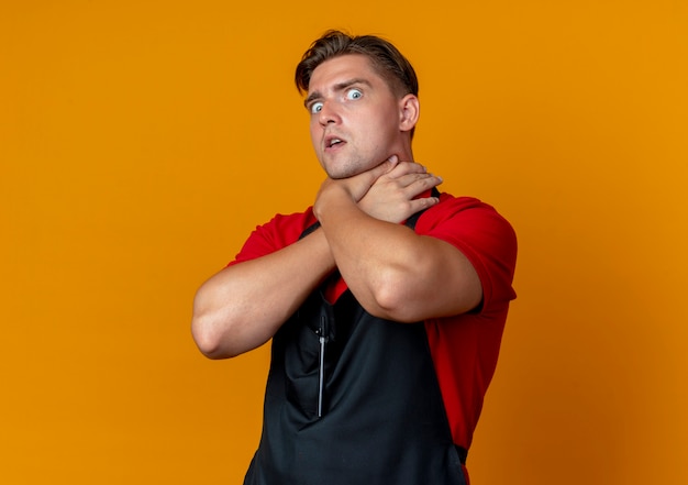 Free photo young scared blonde male barber in uniform pretends to choke himelf with hands isolated on orange space with copy space