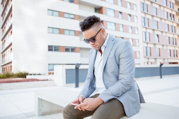 Young Serious Businessman Texting Message on Bench