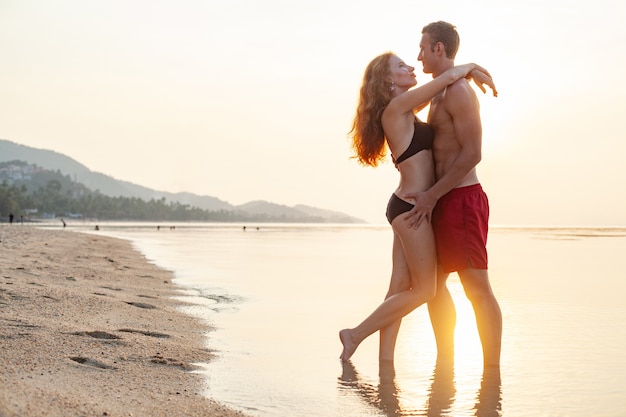 Young sexy romantic couple in love happy on summer beach together having fun wearing swim suits