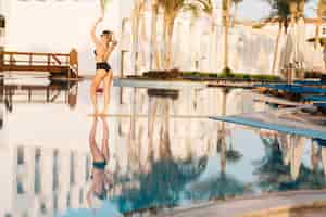 Free photo young sexy woman, wearing fashionable black swimsuit, bikini, near big nice pool, resort. hotel. happy summer time, vacation, holiday, spa