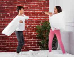 Free photo young siblings at home fighting with pillows