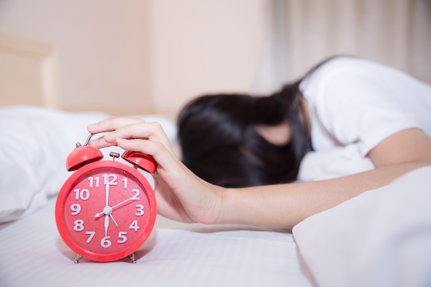 Young sleeping woman and alarm clock in bedroom at home 