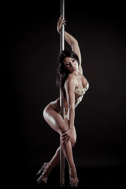 Young slim pole dance woman on a black studio background