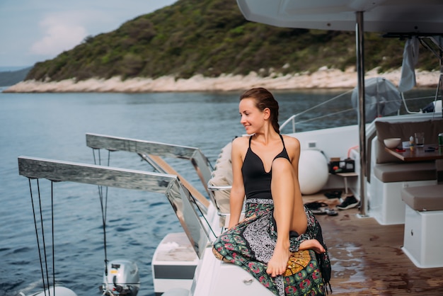 Free Photo young slim woman sitting in bikini bathing suit on a yacht and basking in the sun