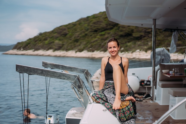 Free Photo young slim woman sitting in bikini bathing suit on a yacht and basking in the sun