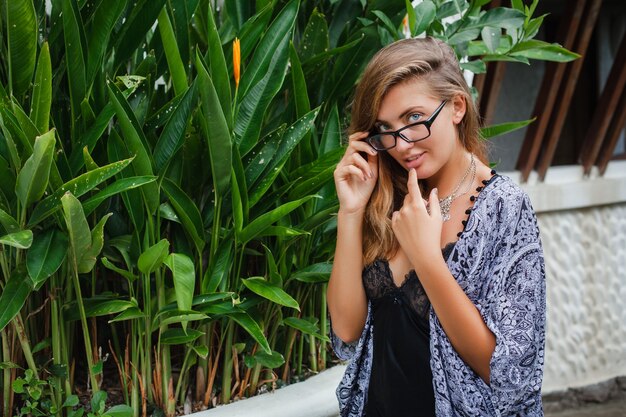 Young slim woman in tropical Bali villa, wearing glasses and lingerie