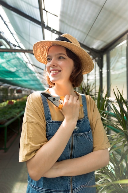 Young smiley woman working in a greenhouse