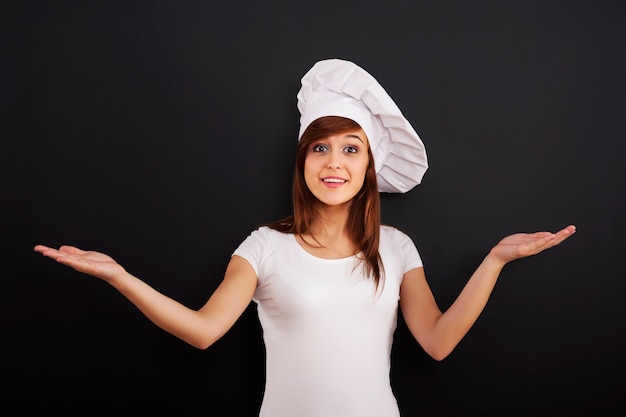 Young smiling cooking chef showing greeting sign