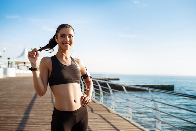 young smiling fitness girl ready for sport exercises by the sea