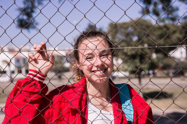 Young smiling girl standing behind grid