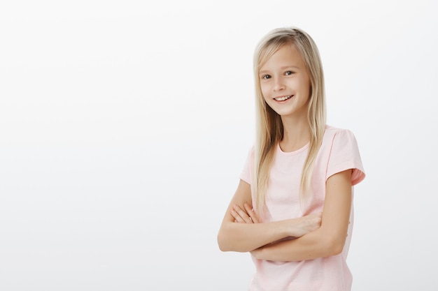 Young smiling kid looking happy. Small woman standing over white wall cheerful