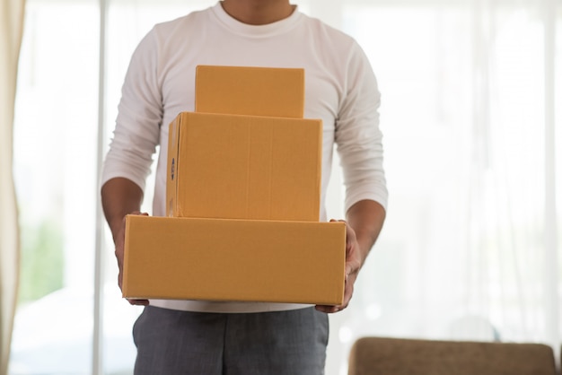 Young smiling logistic delivery man holding the box 