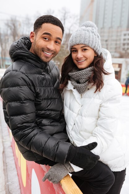 Young smiling loving couple skating at ice rink outdoors.