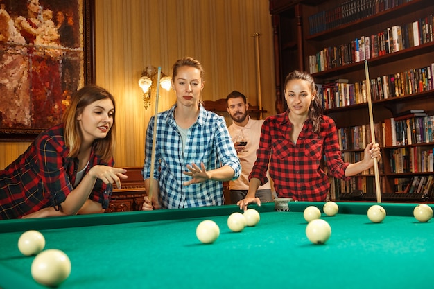 Free photo young smiling men and women playing billiards at office or home after work. business colleagues involving in recreational activity. friendship, leisure activity, game concept.