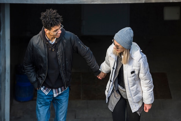 Free photo young smiling stylish couple holding each other's hand making fun