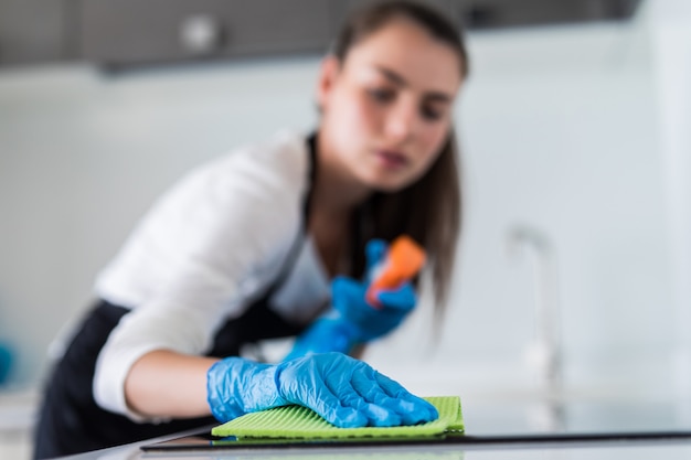 Young smiling woman cleans the kitchen at her home