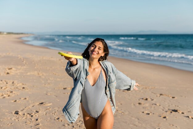 Young smiling woman playing frisbee on seashore