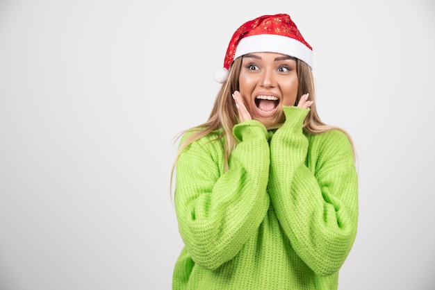 Free Photo young smiling woman posing in santa claus red hat .