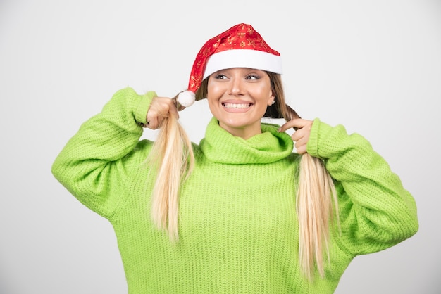 Free photo young smiling woman posing in santa claus red hat .