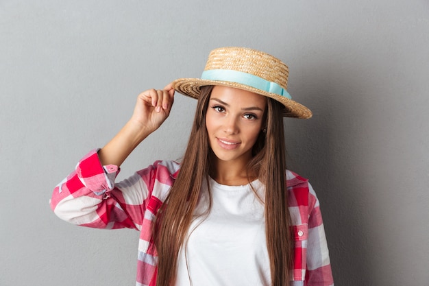 Young smiling woman in straw hat and checkered shirt