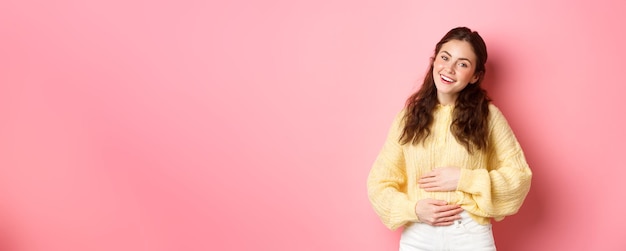 Free photo young smiling woman touching her stomach with relieved happy face feeling good after eating yoghurt