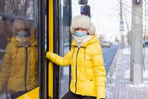 Free photo young smiling woman walks into the bus on a winter day