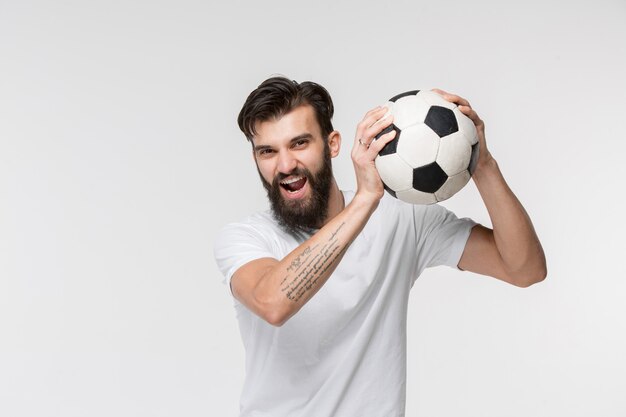 Young soccer player with ball in front of white wall