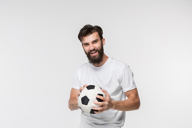 Young soccer player with ball in front of white wall