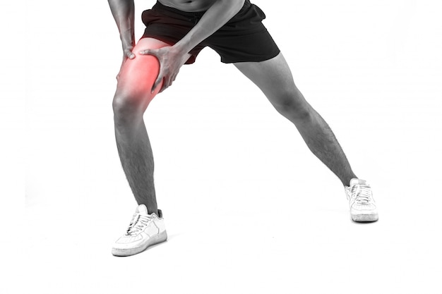 Young sport man with strong athletic legs holding knee with his hands in pain after suffering ligament injury  isolated on white.