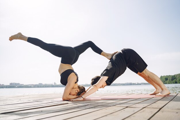 Young sportive couple doing yoga fitness . People by the water.