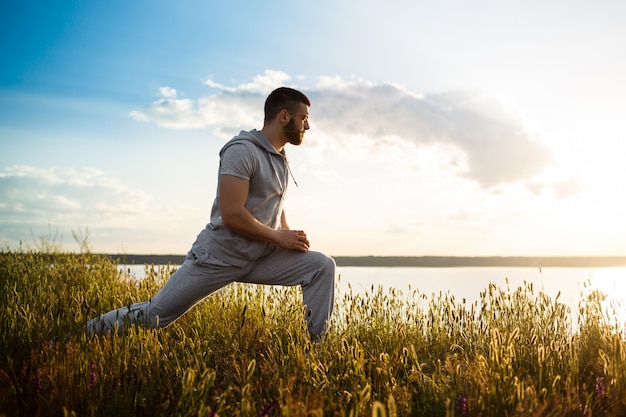 Young sportive man training in field at sunrise.