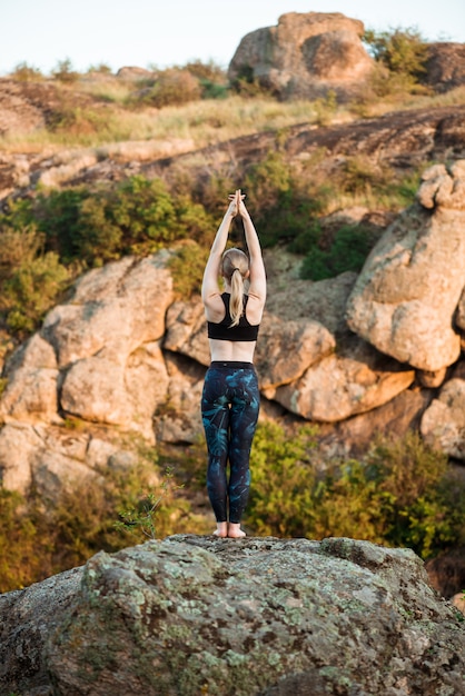 Free Photo young sportive woman training yoga asanas on rock in canyon