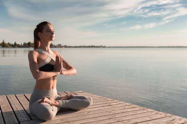 Young sports lady at the beach make meditation exercises.