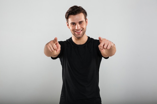 Young sports man pointing to you.