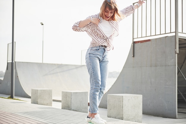 Free photo a young sports woman who rides in a park on a skateboard.