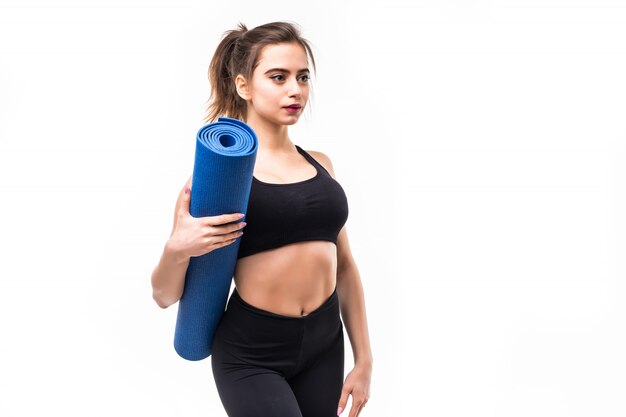 Young sportswoman in black sportswear practicing yoga on a mat.